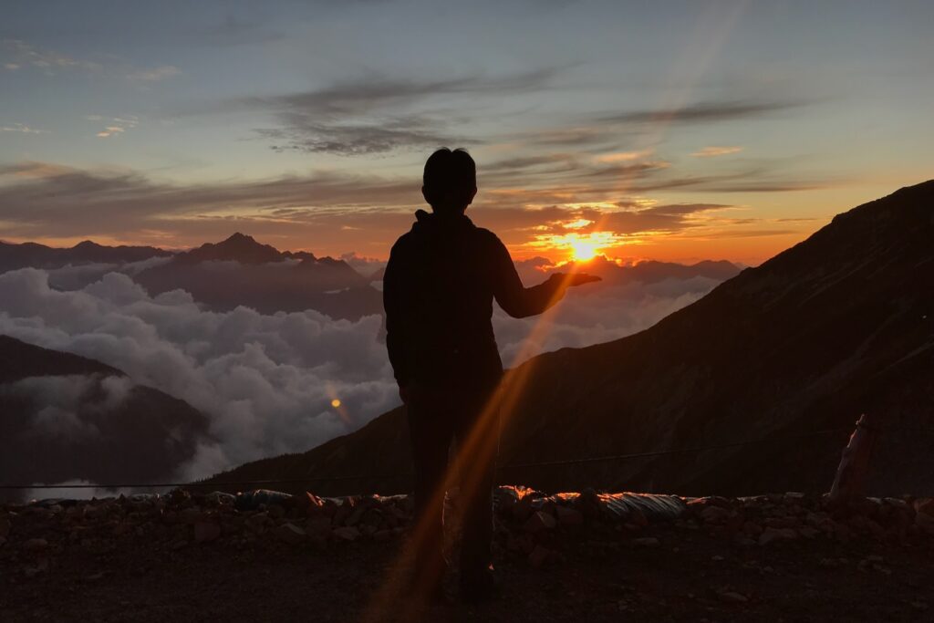 夕陽と雲海を眺める登山者のシルエット