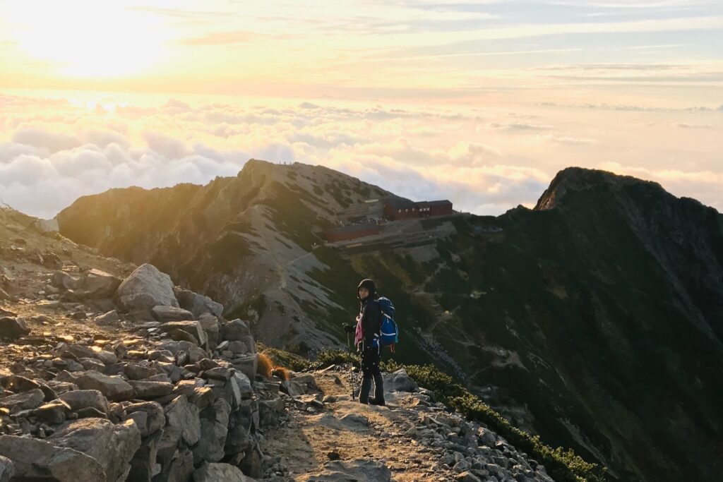 朝日を浴びながら山荘へと稜線を下る登山者