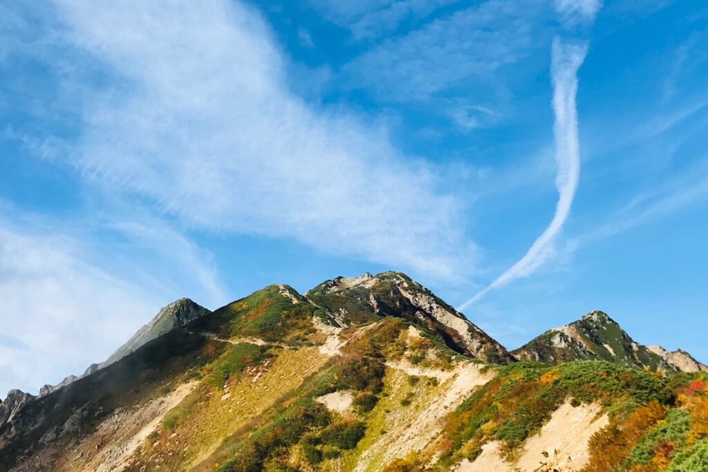 秋晴れの空と紅葉に色づく唐松岳周辺の稜線