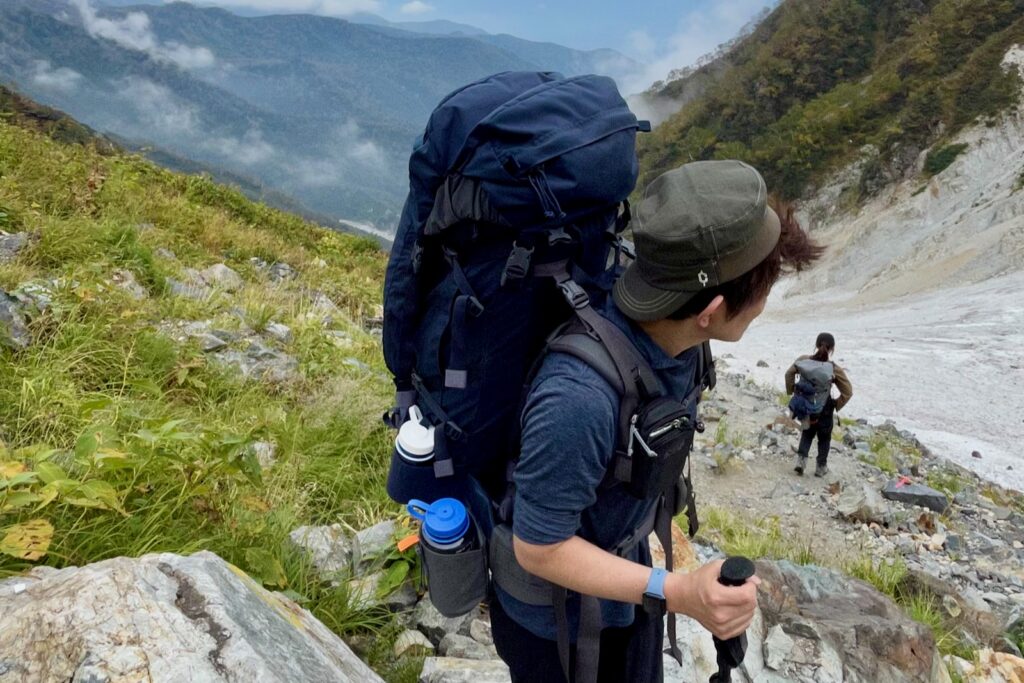 大きなザックを背負って急登を登る登山者