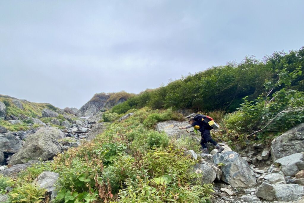 秋道の岩場をよじ登る登山者