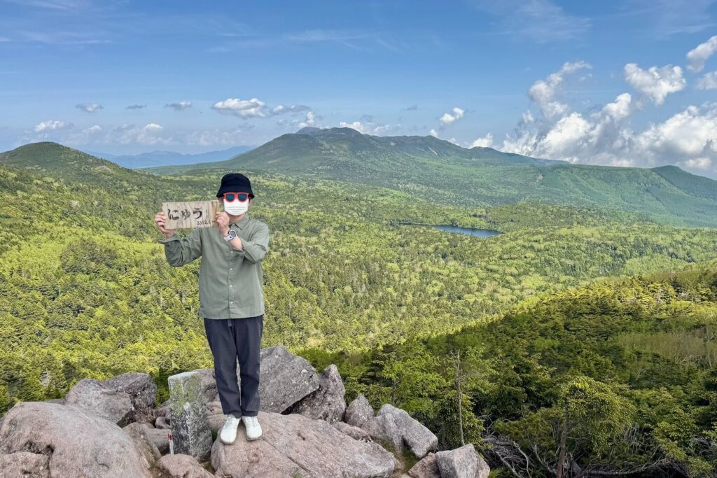 にゅう山頂で標識を持って記念撮影