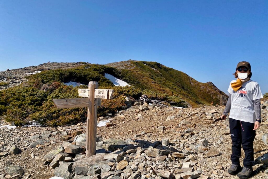 稜線の分岐道標とハイマツ帯に立つ登山者