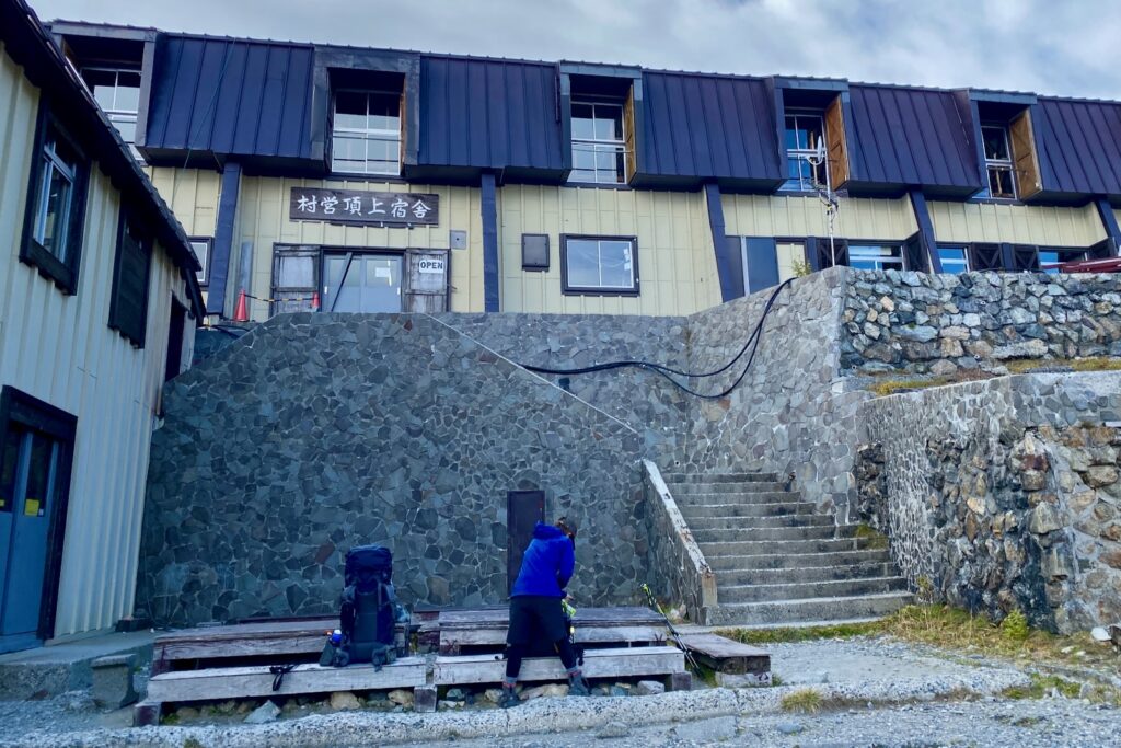 頂上宿舎の前でザックを下ろす登山者