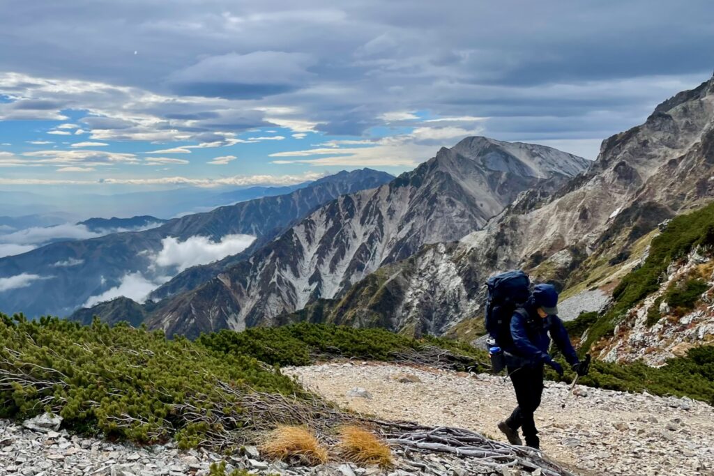 杓子岳と白馬鑓ヶ岳を背に稜線を歩く登山者