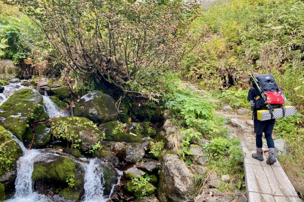 沢にかかる木橋を渡る登山者