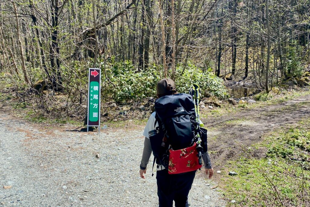 横尾方面を示す案内板に沿って迂回路を進む登山者