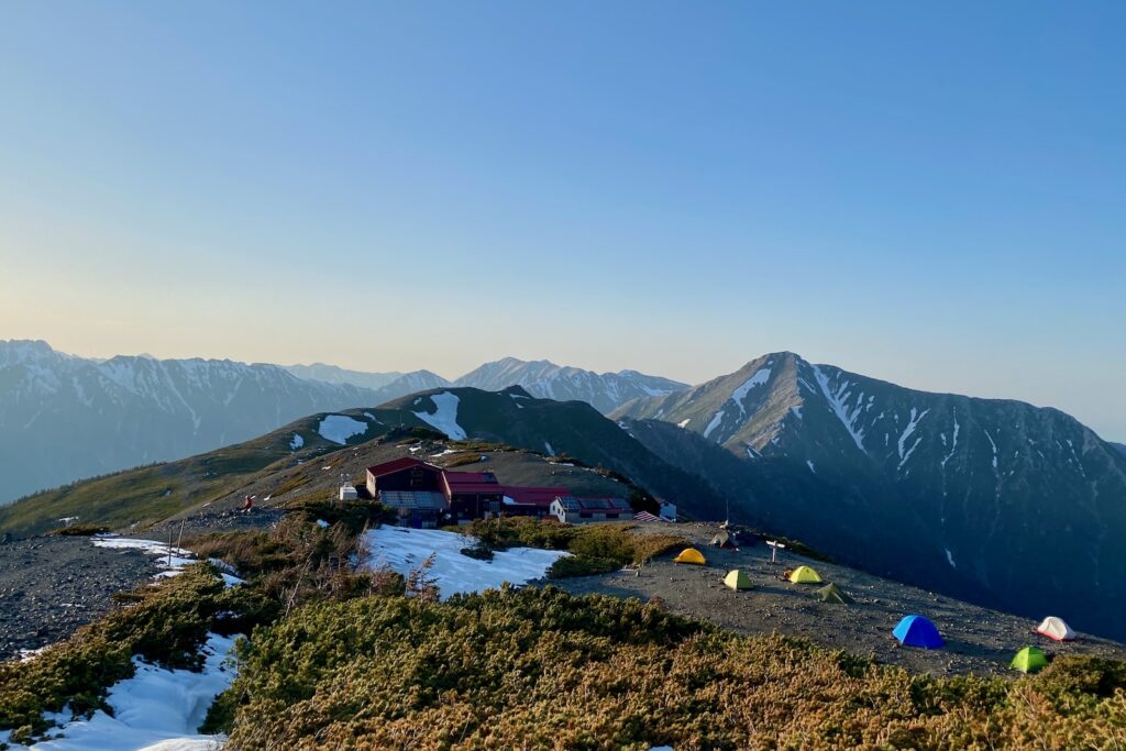 夕方の蝶ヶ岳ヒュッテとテント場、奥に常念岳