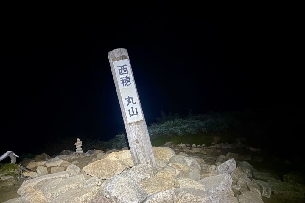 暗闇の中の「西穂 丸山」の標柱