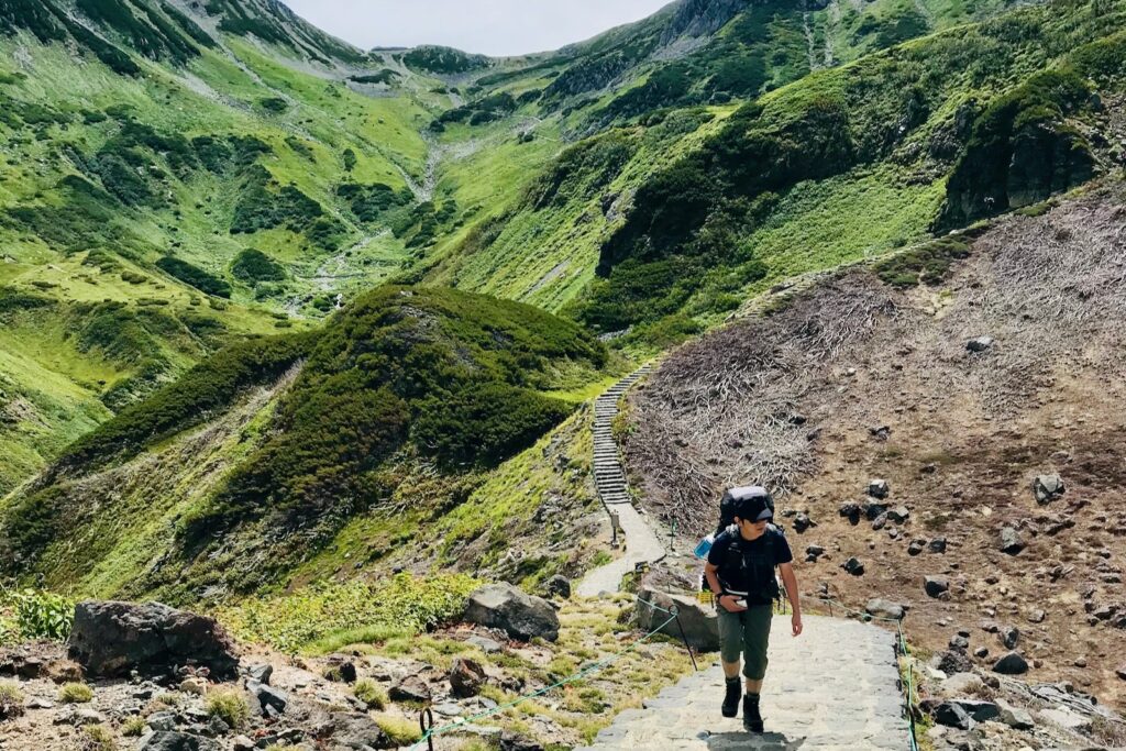荒涼とした谷を横目に雷鳥沢へ続く道を歩く登山者