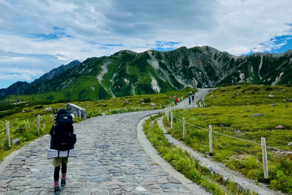 室堂平の石畳の道を大きなザックで歩く登山者
