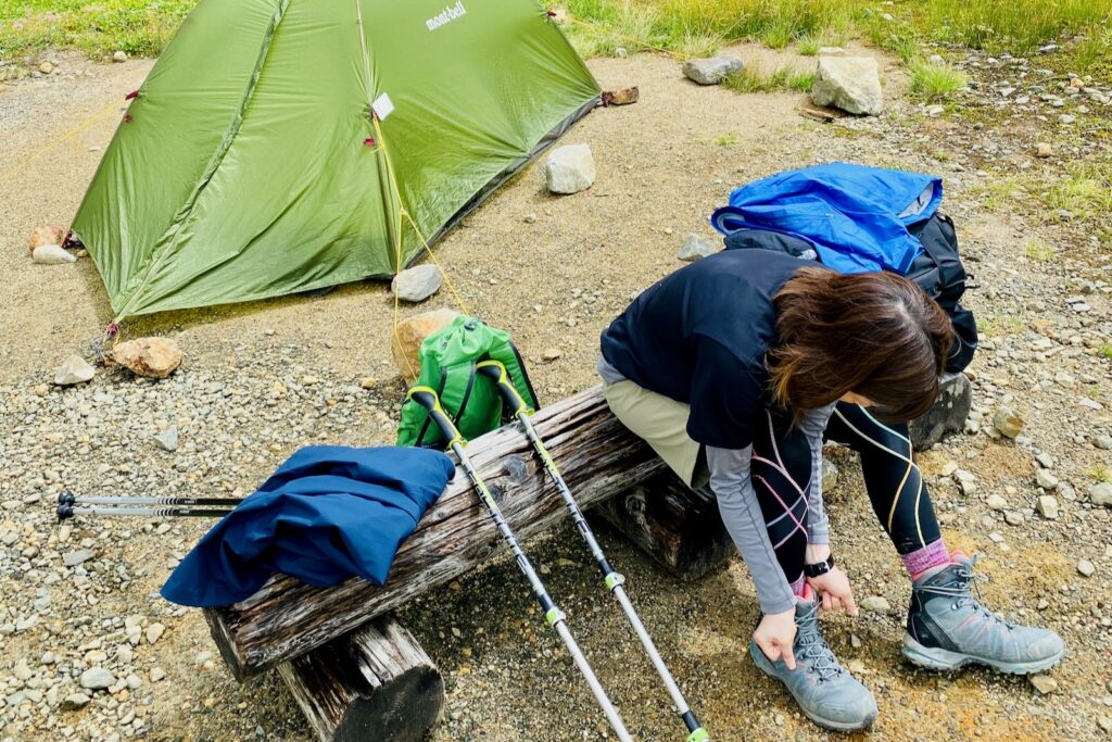 雷鳥沢キャンプ場のテント前のベンチで靴を履き替える登山者